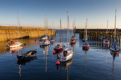 Sailboats moored in sea against clear sky