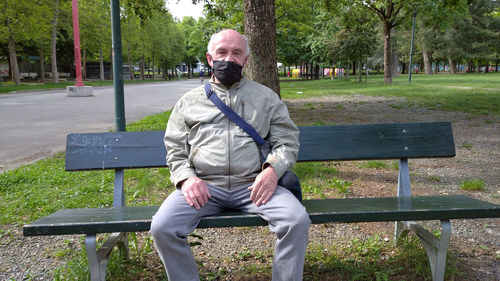Portrait of man sitting on bench in park