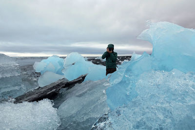 Man photographing on frozen beach