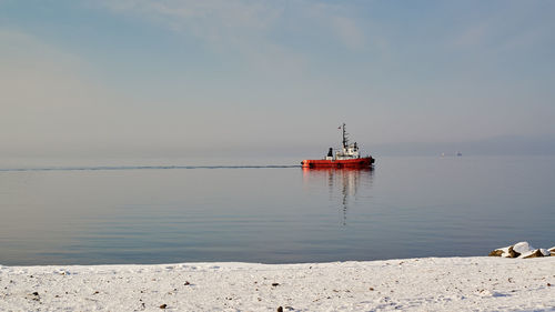 Tugboat on sea against sky.