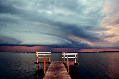 Pier over sea against dramatic sky