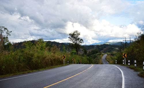 Road by trees against sky