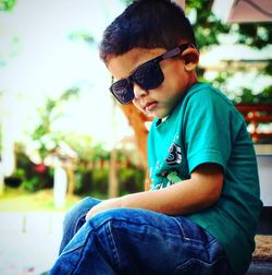 Side view of boy wearing sunglasses sitting outdoors