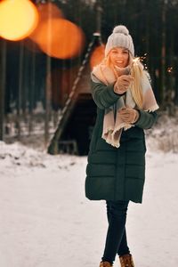 Full length of woman standing on snow holding sparkler