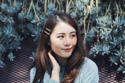 Close-up of thoughtful young woman sitting against plants