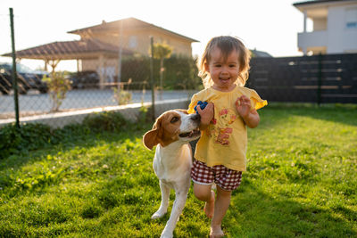 Portrait of cute baby girl with dog on field