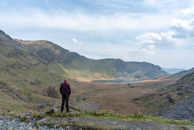 Rear view of man standing on mountain against sky