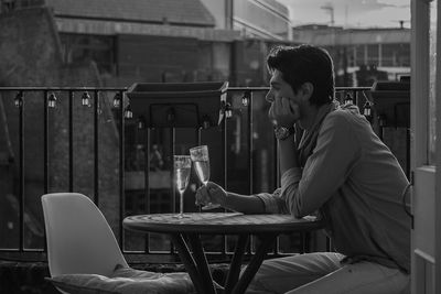 Side view of sad young man with wine while sitting at restaurant