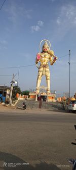 Statue by road against sky in city