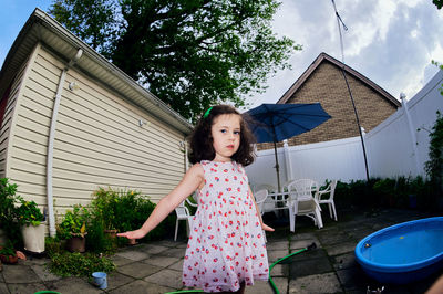 Cute young girl in a summer dress playing in a suburban backyarrd