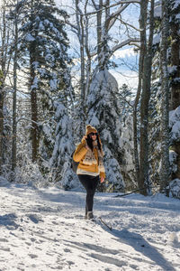 Full length photo of woman wearing winter clothes, hiking in snowy winter forest