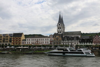 Boats in river by buildings against sky in city