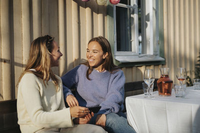 Happy young women talking to each other during dinner party at cafe