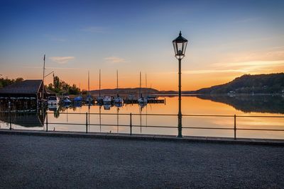 Sailboats moored in river against sky during sunset