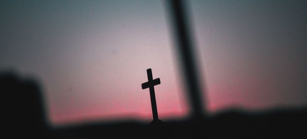 Close-up of silhouette cross against sky during sunset