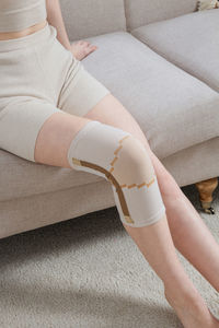 Low section of woman sitting on sofa at home