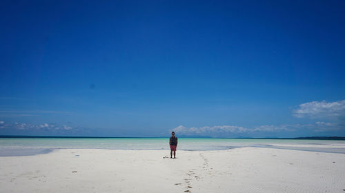 Man on beach against blue sky