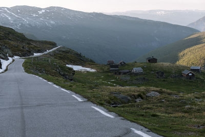 Scenic view of road by mountains against sky