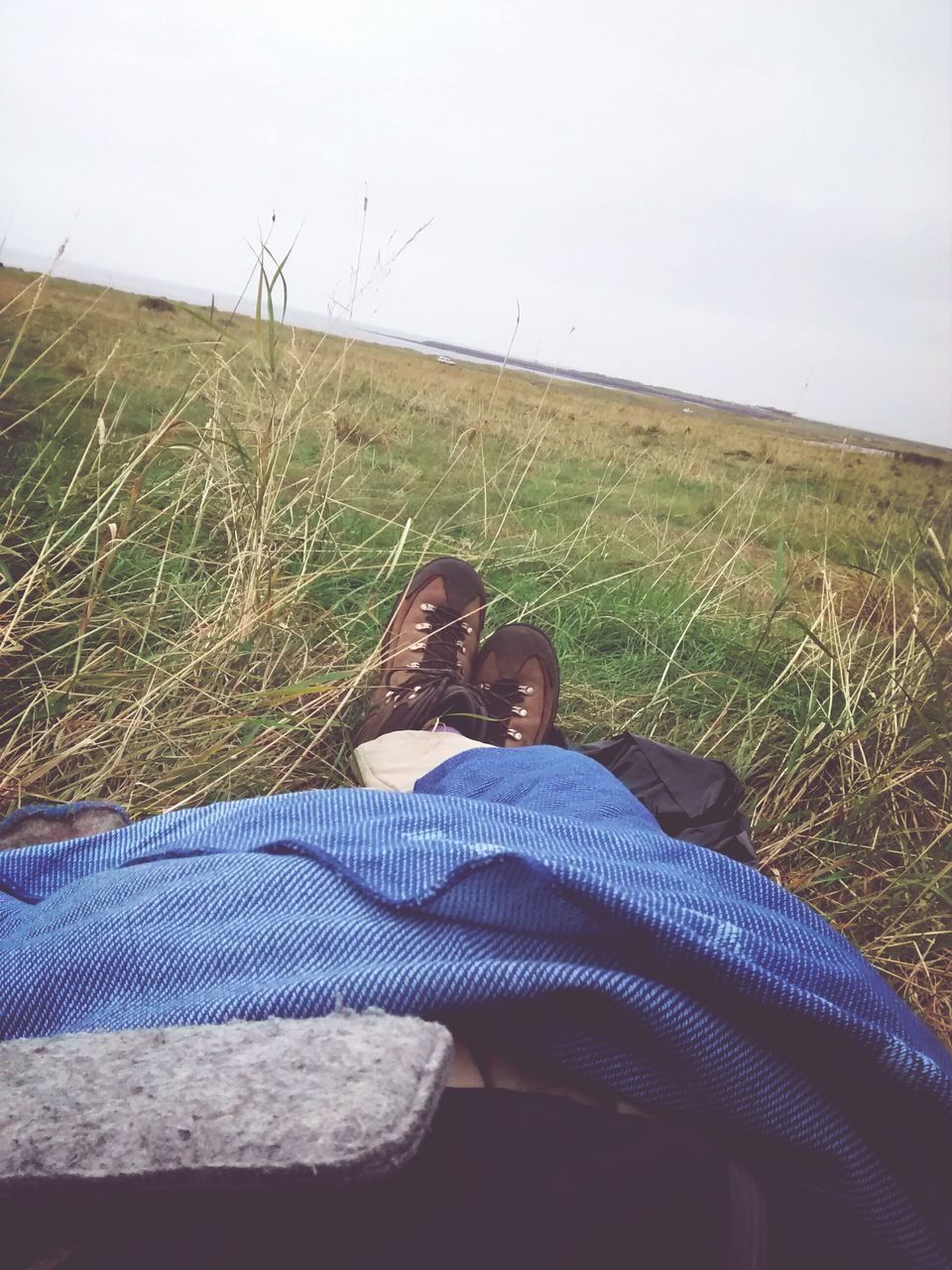 low section, grass, lifestyles, person, leisure activity, relaxation, field, sitting, grassy, shoe, personal perspective, casual clothing, men, resting, landscape, nature, relaxing
