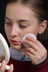 Close-up of young woman applying make-up