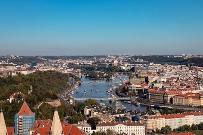 High angle view of river amidst buildings against blue sky