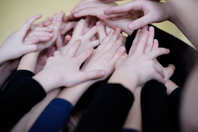 Cropped hands of friends against wall