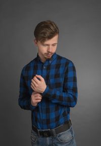 Portrait of young man standing against black background