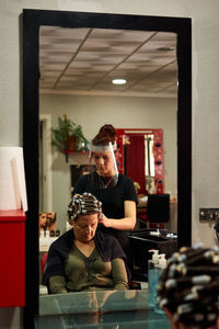 Hairdresser combs a client with a face shield in her salon