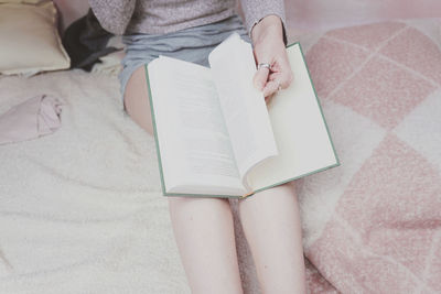 High angle view of woman reading book on bed