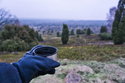 Midsection of person against trees on landscape against sky