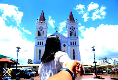 Rear view of man and woman against sky in city