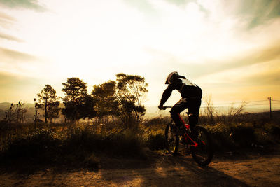 Silhouette man with bicycle against sky during sunset