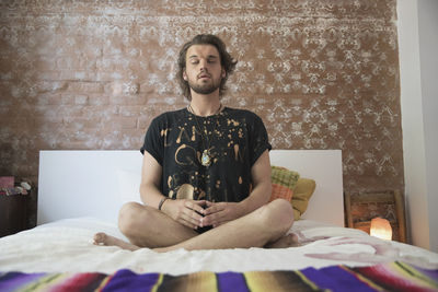 Young man meditating on his bed