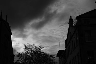 Low angle view of silhouette buildings against cloudy sky