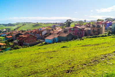 Houses on field by buildings against sky