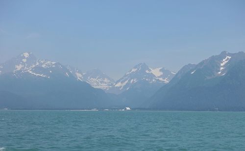 Scenic view of sea and snowcapped mountains against sky