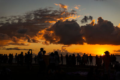 Dramatic sunset in salvador, bahia at farol da barra beach with silhouettes of people 