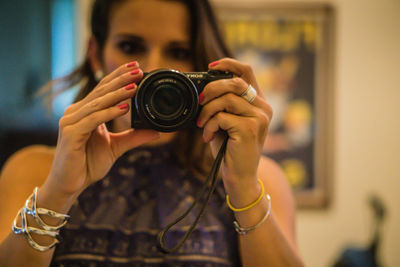 Young woman photographing through camera at home