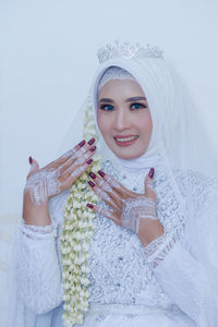 Portrait of young woman wearing hijab against white background