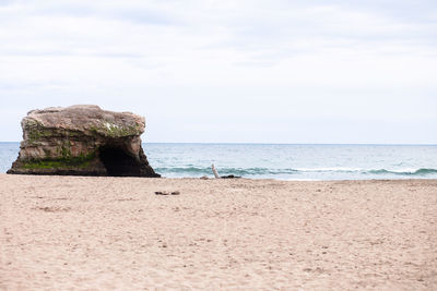 Rock formation on beach against sky