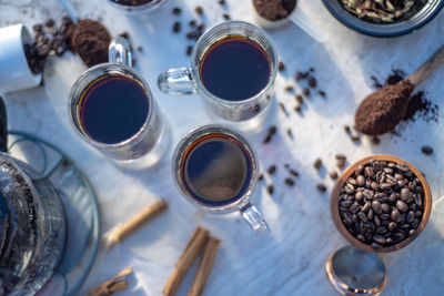 Still life with glass mugs of black hot coffee, coffee beans, making coffee at home