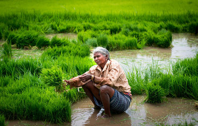 Man sitting on field by river