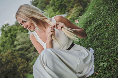 Fashionable woman wearing dress sitting on grass