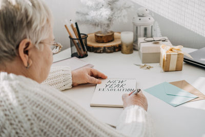 Healthy new years resolutions for older adults. senior mature old woman in white sweater writing