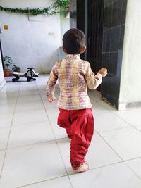 Rear view of woman standing on tiled floor