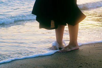 Low section of man standing on beach