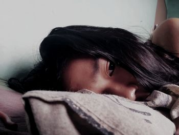 Close-up of thoughtful young woman relaxing on bed at home