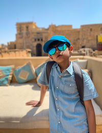 Man wearing sunglasses standing against built structure