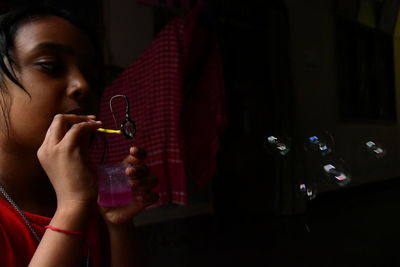 Girl blowing bubbles in darkroom