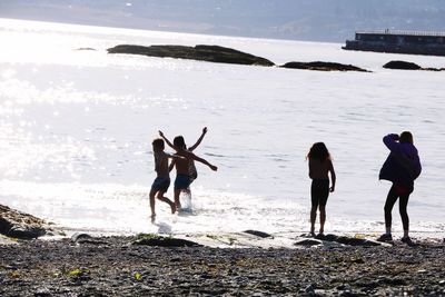 Rear view of people at beach against sky